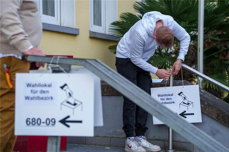 Wahlhelfer hängen Hinweisschilder für die Kommunalwahl auf.Andreas Arnold/dpa