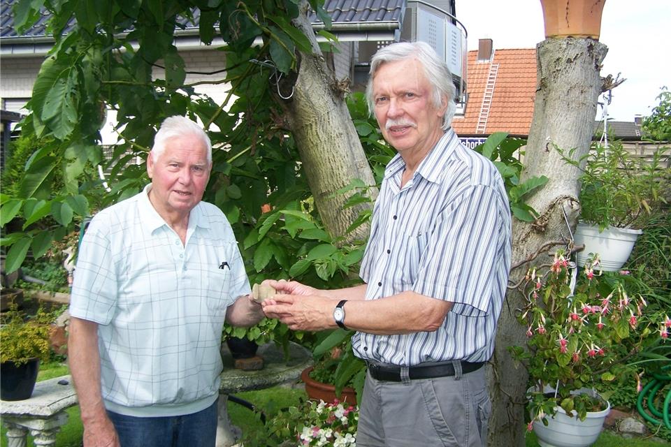 Walter Biermann (links) überreicht Norbert Sabellek das Fragment eines steinzeitlichen Steinbeils.