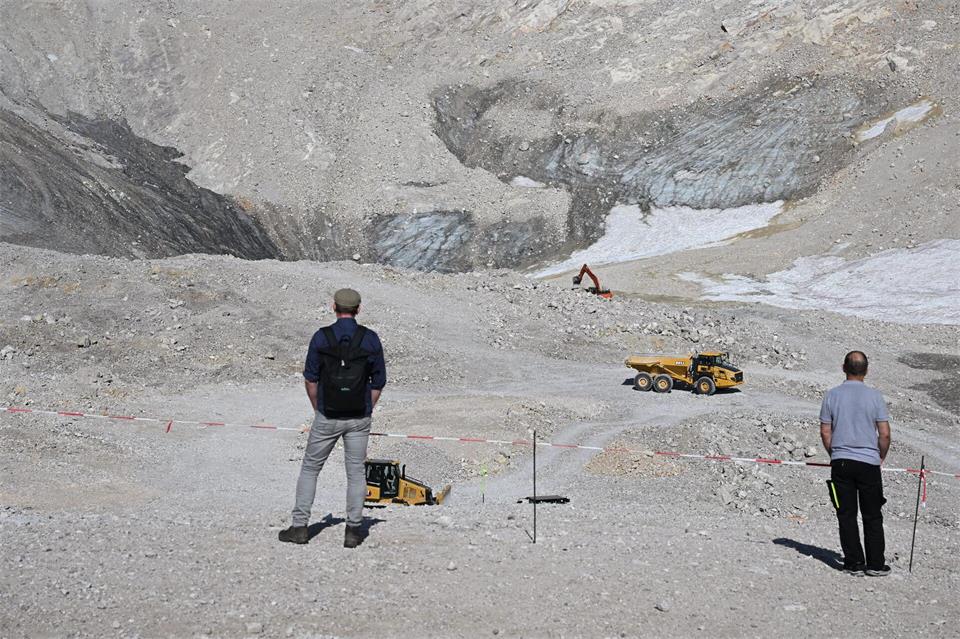 Wanderer beobachten Baumaschinen neben den Überresten des Nördlichen Schneeferner-Gletschers auf der Zugspitze.Angelika Warmuth/dpa