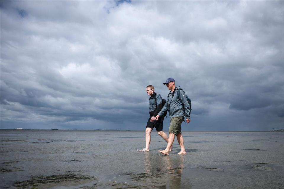 Wattwanderung vor dramatischer Wolkenkulisse.Christian Charisius/dpa