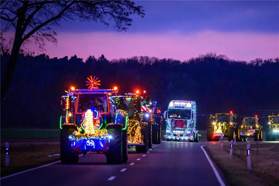 Weihnachtlich beleuchtete und geschmückte Traktoren und Lkw sind bei der Lichterfahrt der Oderlandbauern in Brandenburg unterwegs. Patrick Pleul/dpa