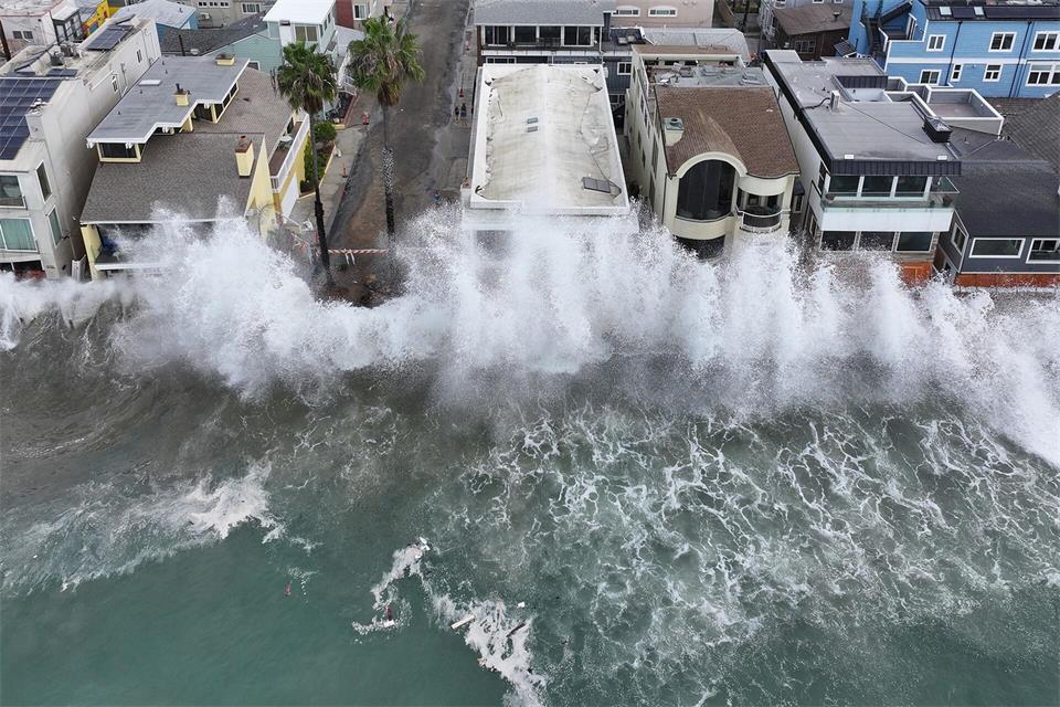 Wellen treffen auf einen einen Gehweg vor einigen Häusern in Long Beach, während sich der Tropensturm „Rachel“ nähert.William Liang/AP/dpa