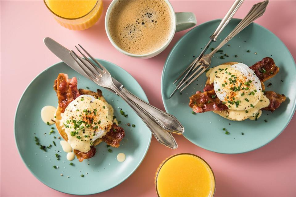 Wie ein Schuss flüssiges Gold fließt die Hollandaise bei Eggs Benedict über pochierte Eier auf Bacon und halbierten englischen Muffins.picture alliance / dpa-tmn
