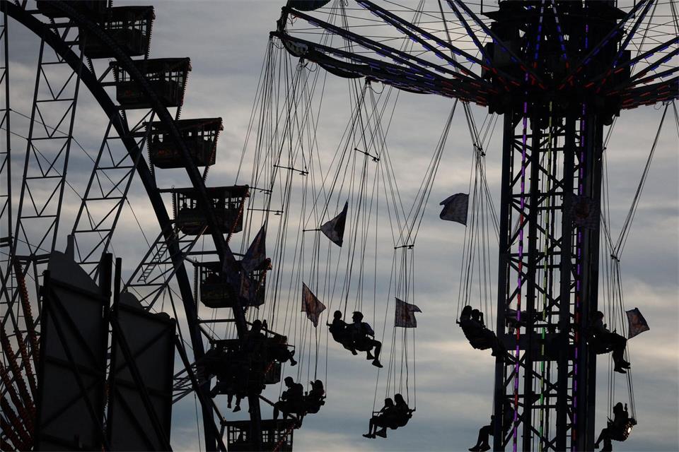 Wiesn-Besucher sitzen am Abend in einem Karussell vor dem Riesenrad auf dem Oktoberfest.Karl-Josef Hildenbrand/dpa