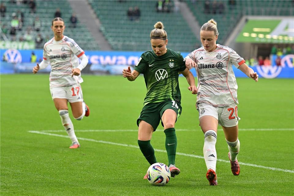 Wolfsburgs Svenja Huth (M) im Zweikampf mit Franziska Kett vom FC Bayern München.Swen Pförtner/dpa
