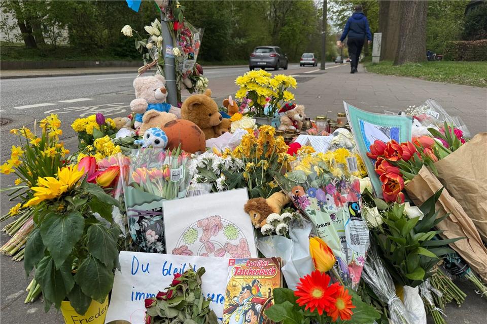 Zahlreiche Blumen und andere Dinge liegen an dem Ort, an dem das Kind vor wenigen Tagen von einem Lastwagen überfahren und getötet wurde.Christiane Bosch/dpa