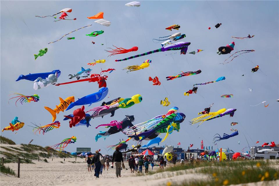 Zahlreiche bunte Drachen sind beim Drachenfest über dem Strand von St. Peter-Ording in der Luft. Zu sehen sind überdimensionale Kreationen, Lenkdrachen, Unikate und beliebte Comicfiguren.Christian Charisius/dpa
