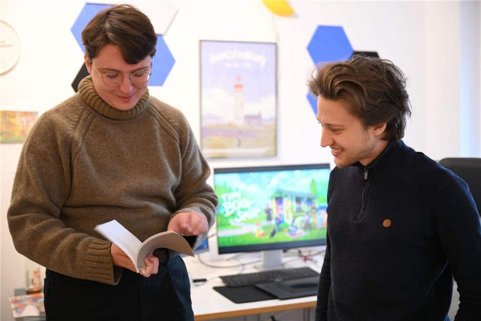 Zapfe-Wildemann hält ein Heft in der Hand, in dem Regeln für eine analoge Version von „Tiny Bookshop“ stehen.Wolf von Dewitz/dpa