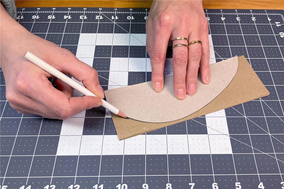 Zeichnen Sie eine halbe Ei-Form auf Karton vor und übertragen Sie diese insgesamt 12-mal auf Ihre Kraftpapierbögen.DIY Academy/dpa-tmn