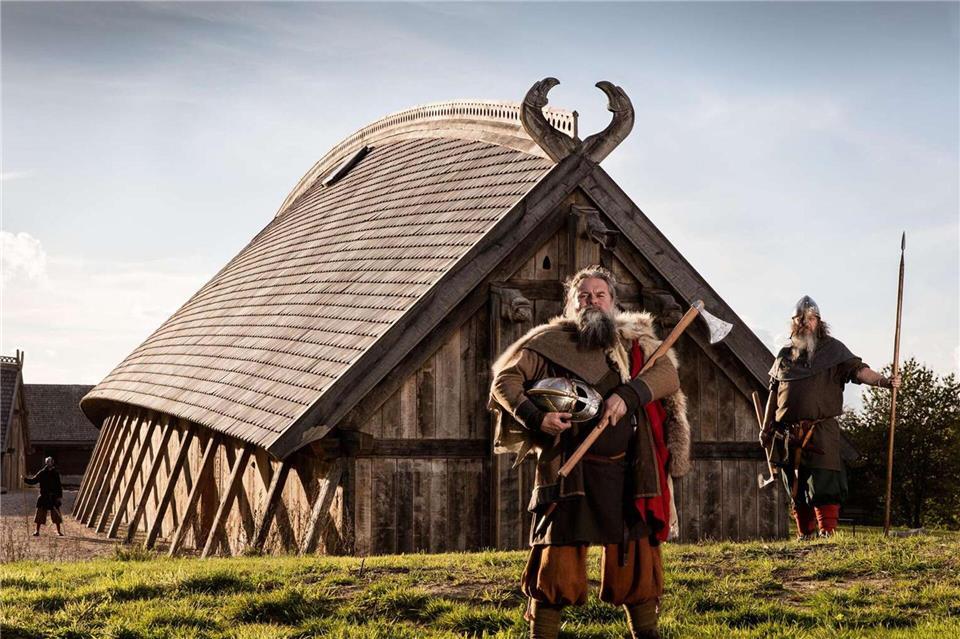 Zeitreise: Als Wikinger verkleidete Schauspieler stehen vor der Königshalle im „Land der Legenden“.Sagnlandet Lejre/Visit Fjordlandet/dpa-tmn