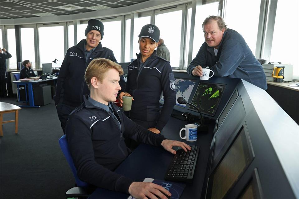 Zöllner Sven-Erik Dröse (Lukas Zumbrock, sitzend) kommt einer heißen Spur auf die Schliche in einer Szene aus der Folge „Geschäft mit dem Tod“ aus der Krimireihe „Der Bremerhaven-Krimi“ - hinten von links nach rechts: Elena Uhlig, Cynthia Micas, Bernd Hölscher.Jörg Landsberg/Radio Bremen/ARD/dpa