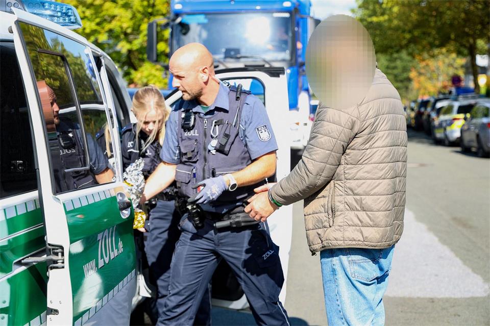 Zollfahnder führen nach den Durchsuchungen einen Mann ab.Gianni Gattus/dpa