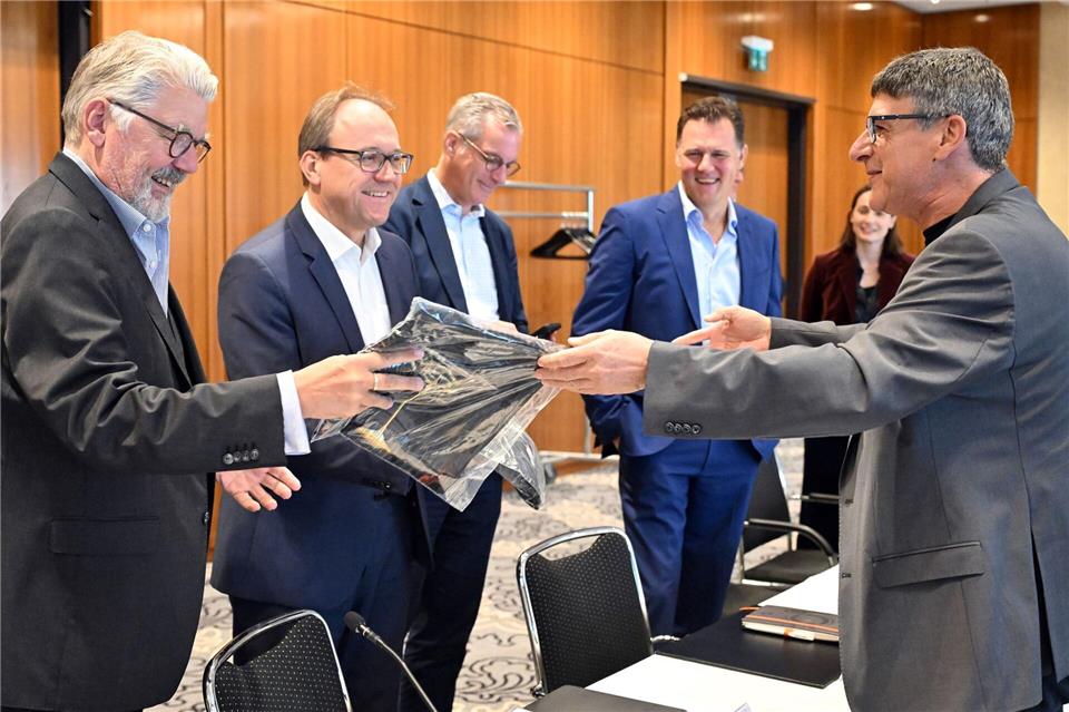Zum Beginn der Tarifverhandlungen in der Stahlindustrie überreicht der Verhandlungsführer der IG Metall, Knut Giesler, zwei T-Shirts an den Verhandlungsführer der Arbeitgeber, Reiner Blaschek (2.v.l), sowie den Geschäftsführer des Arbeitgeberverbandes Stahl, Gerhard Erdmann (l).Federico Gambarini/dpa