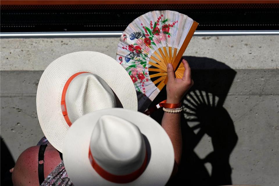Zuschauer kühlen sich an einem heißen Tag mit Handfächern bei den Tennis French Open.Christophe Ena/AP/dpa