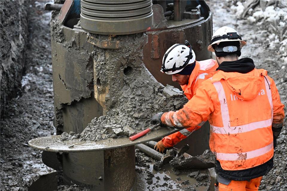Zwei Bauarbeiter bereiten eine Bohrung mit dem Großbohrgerät auf der Baustelle für den Riederwaldtunnel vor.Michael Brandt/dpa