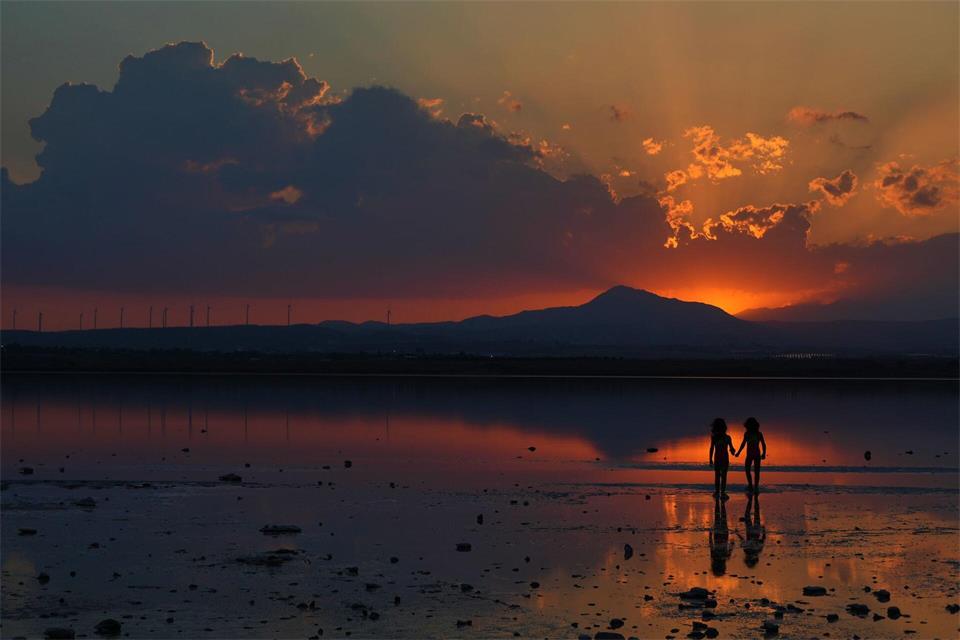 Zwei Mädchen spielen bei Sonnenuntergang am Salzsee in der südlichen Küstenstadt Larnaca auf Zypern.Petros Karadjias/AP/dpa