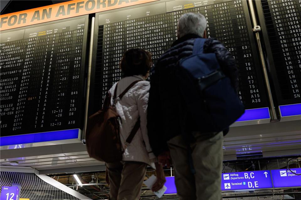 Zwei Menschen schauen auf eine Anzeigetafel mit annullierten Flügen am Frankfurter Flughafen.Hannes P. Albert/dpa