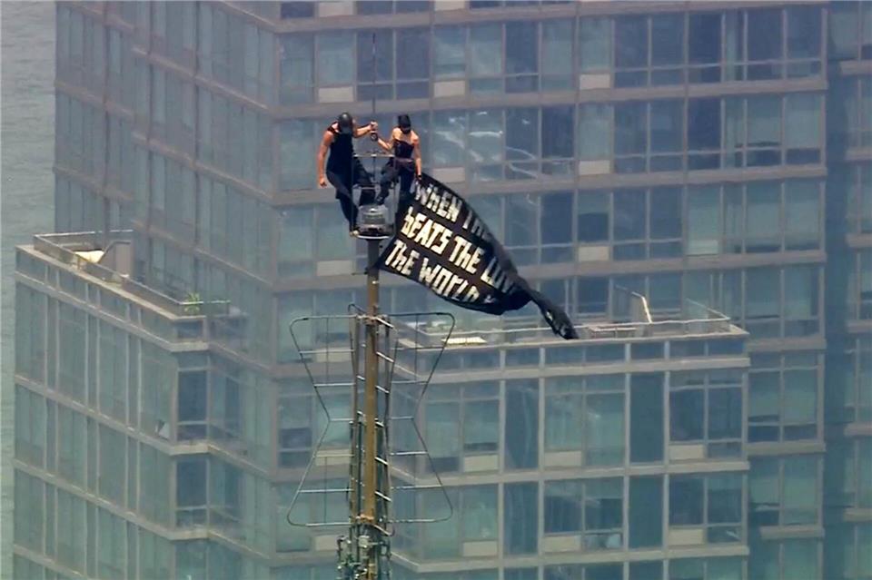 Zwei Menschen stehen auf der Spitze der Antenne des Empire State Building mit einem Banner.Uncredited/WABC-TV/AP/dpa