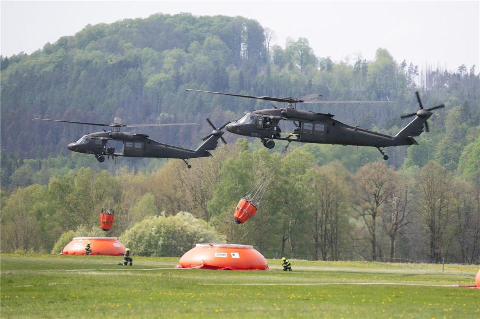 Zwei Transporthubschrauber des Typs Sikorsky UH-60 Black Hawk mit Löschwasser-Behältern aus der Slowakei beim Landeanflug auf den Flug- und Landeplatz Chribska im Nationalpark Böhmische Schweiz.Sebastian Kahnert/dpa