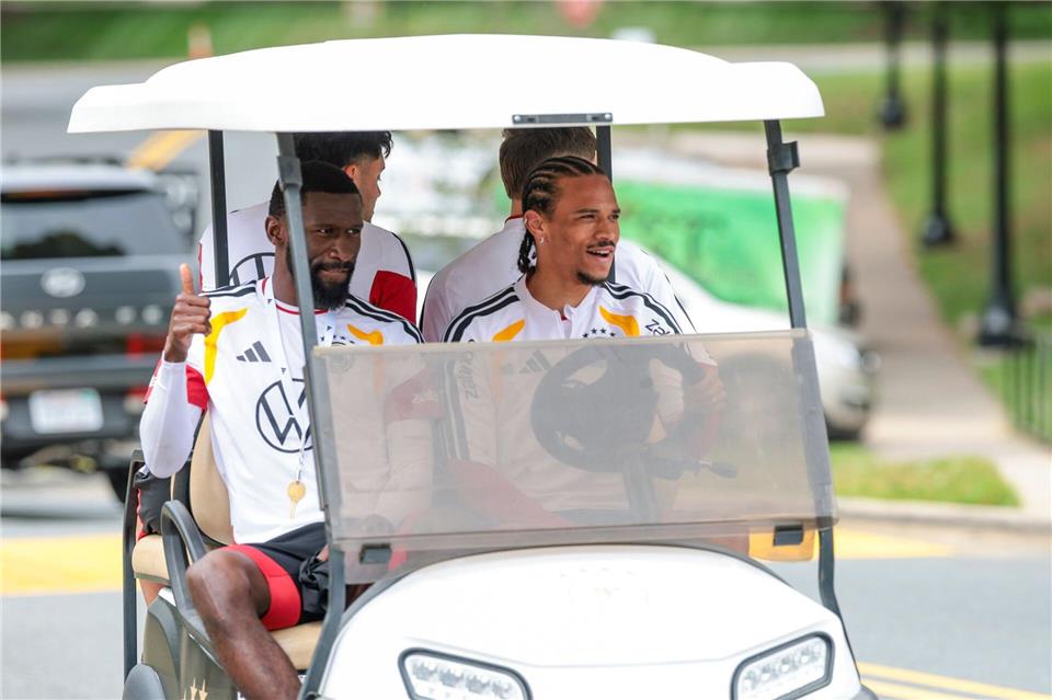 Zwei Umstrittene, die sich bestens verstehen: Beifahrer Antonio Rüdiger und Fahrer Leroy Sané (r) im Golfcart auf dem Weg zum Trainingsplatz. (Archivbild)  Jan Woitas/dpa