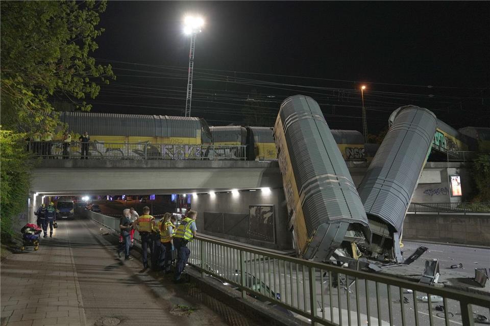 Zwei Waggons eines Güterzugs liegen auf einer Straße in München, nachdem sie von einer Brücke gestürzt sind.Ehsan Monajati/dpa