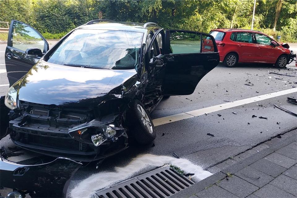 Zwei stark beschädigte Autos stehen nach einem Unfall an einer Kreuzung auf einer Straße.
