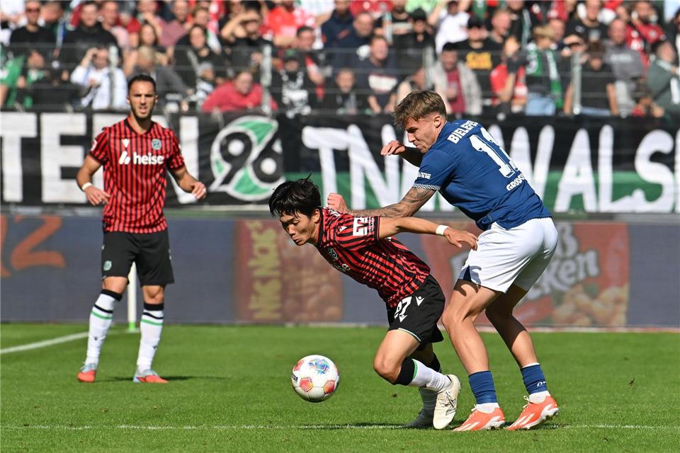 Zweikampf um den Ball: Hayate Matsuda (Hannover 96) wird von Joel Grodowski (Arminia Bielefeld) bedrängt.Swen Pförtner/dpa