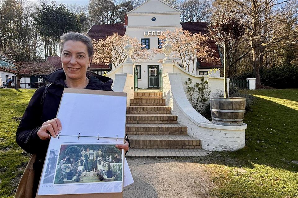 Zweimal Barkenhoff: Mira Awad zeigt an Ort und Stelle das Gemälde „Sommerabend“, das der Künstler Heinrich Vogeler von seinem Wohn- und Atelierhaus malte.Wolfgang Stelljes/dpa-tmn