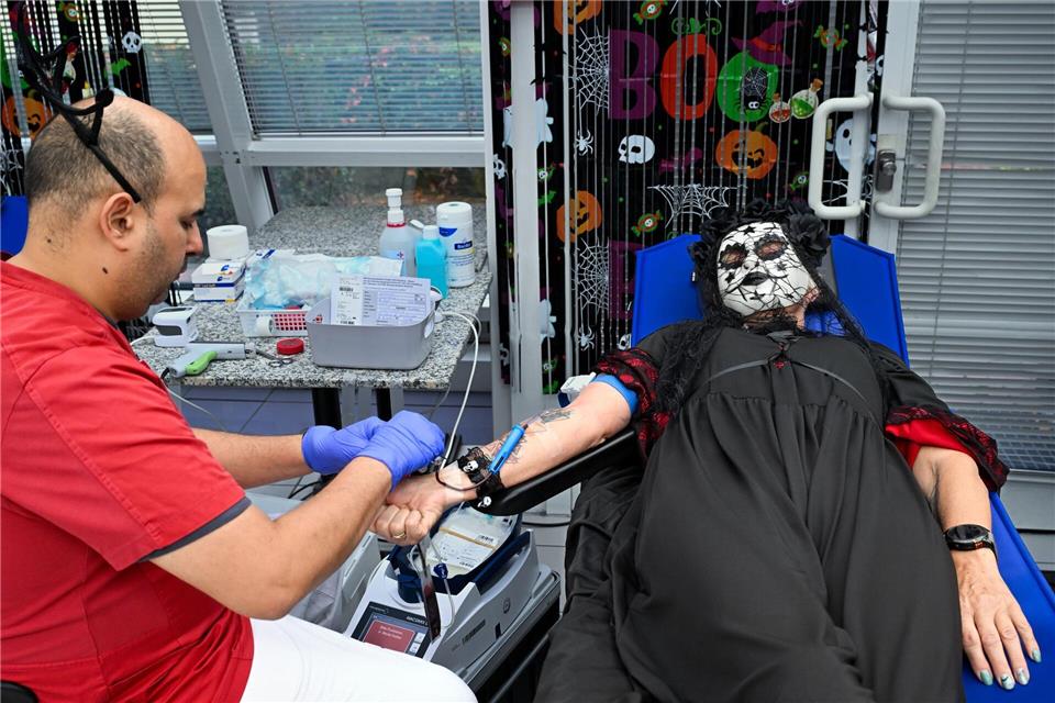 Zwischen Halloween-Deko und im Kostüm spendet eine Frau Blut.Soeren Stache/dpa