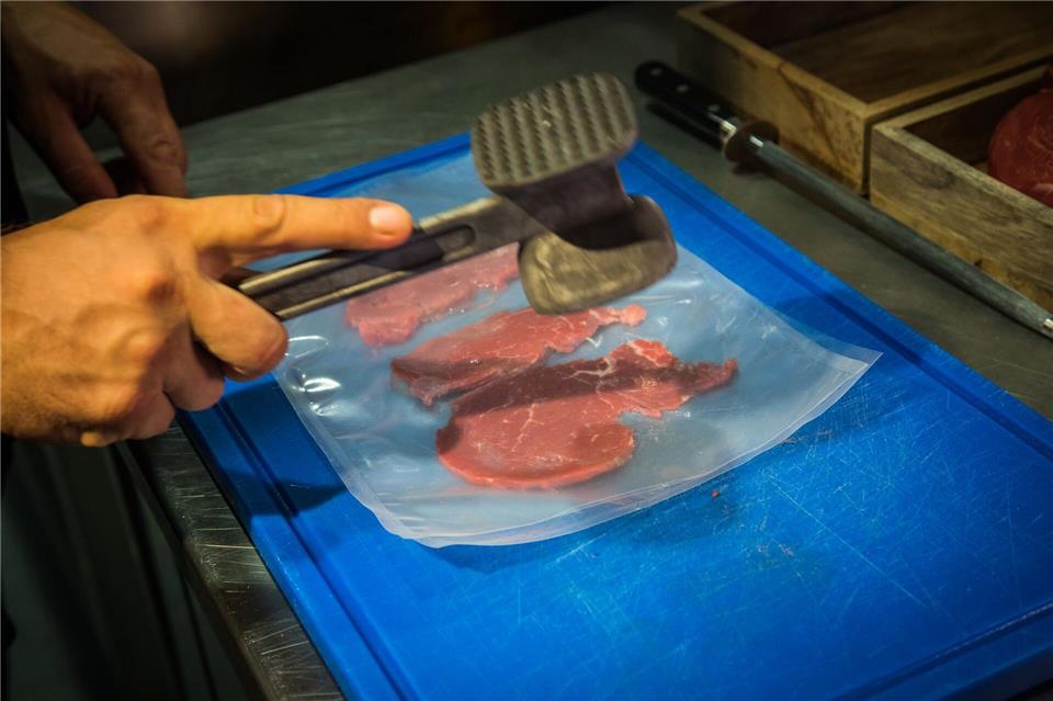 Zwischen zwei Folien gelegt klopft René Tepper in der Küche vom „The Dry Gin and Beef Club“ mit einem Fleischhammer die Rinderfilet-Scheiben - bis sie etwa die dreifache Größe erreicht haben. Christin Klose/dpa-tmn